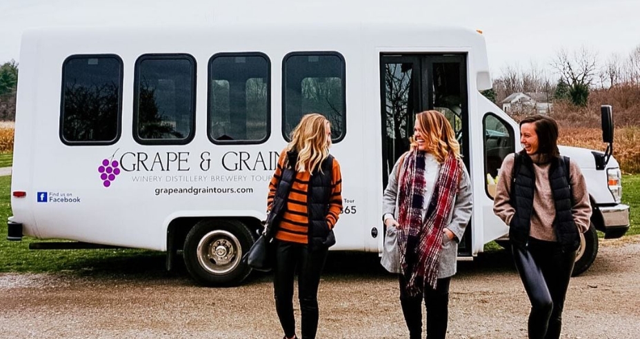 Three friends walking in front of the Grape & Grain Bus.