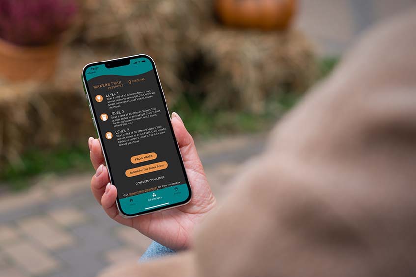 A person holding a phone that is displaying the Makers Trail app.